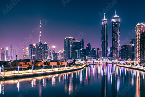 Dubai downtown night city skyline. Skyscrapers and lights are reflected in the water canal.