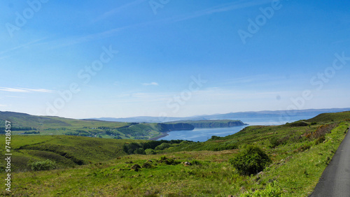 Expansive view of a serene lake with surrounding greenery and a clear sky above.