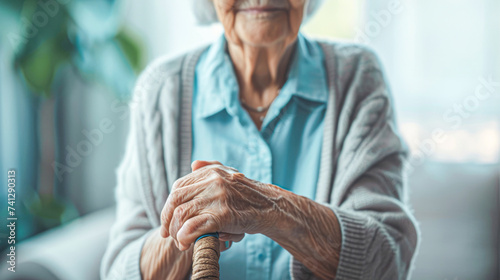 Close-up of an elderly person's hands clasping a wooden cane, symbolizing aging and support. photo