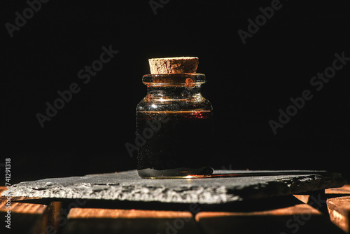 Magic potion bottle on the old wooden table background front view. Witchcraft concept. photo