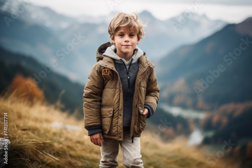 Little boy with blond hair in a warm jacket on the background of mountains