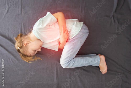 Wallpaper Mural A seven-year-old girl lies and holds her lower abdomen with pain and inflammation of the bladder. Concept of bacterial cystitis in children, hypothermia. Pediatric urology.  Torontodigital.ca