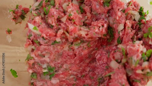 Macro filming, the chef uses a spoon to mix meat, minced beef with onions and herbs in a glass bowl. Close-up, top view, macro