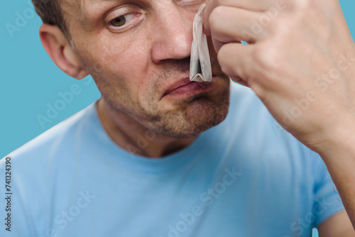 Closeup portrait of sad man with anosmia after infectious disease smelling tea bag. Anosmia assessment: Doctor conducts a test for smell loss. photo