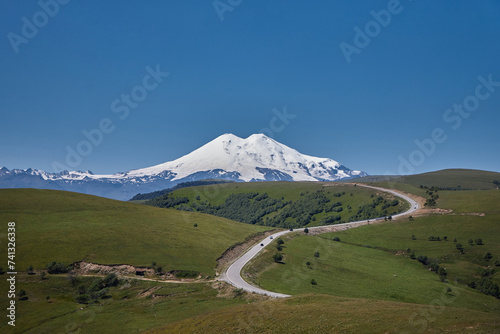 Russia Caucasus, Mount Elbrus towers majestically, adorned in pristine snow and ice. Alpine landscape boasts panoramic views of rugged ridges, serene valleys, and icy glaciers under the vast blue sky