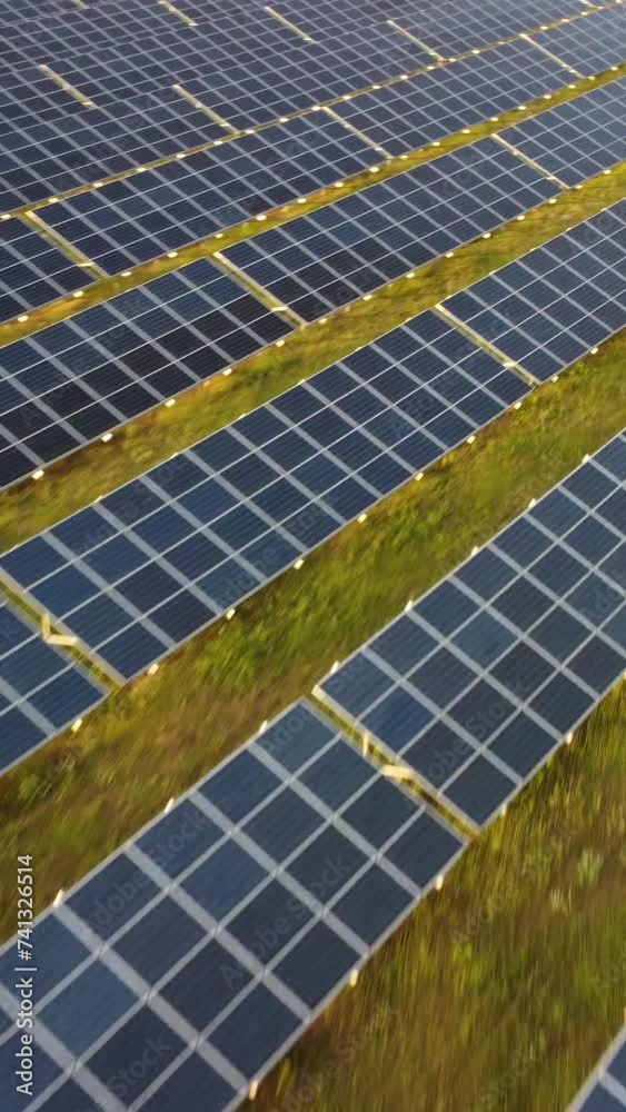Aerial vertical view of a solar panels power plant. Photovoltaic solar panels at sunrise and sunset in countryside from above. Modern technology, climate care, earth saving, renewable energy concept.