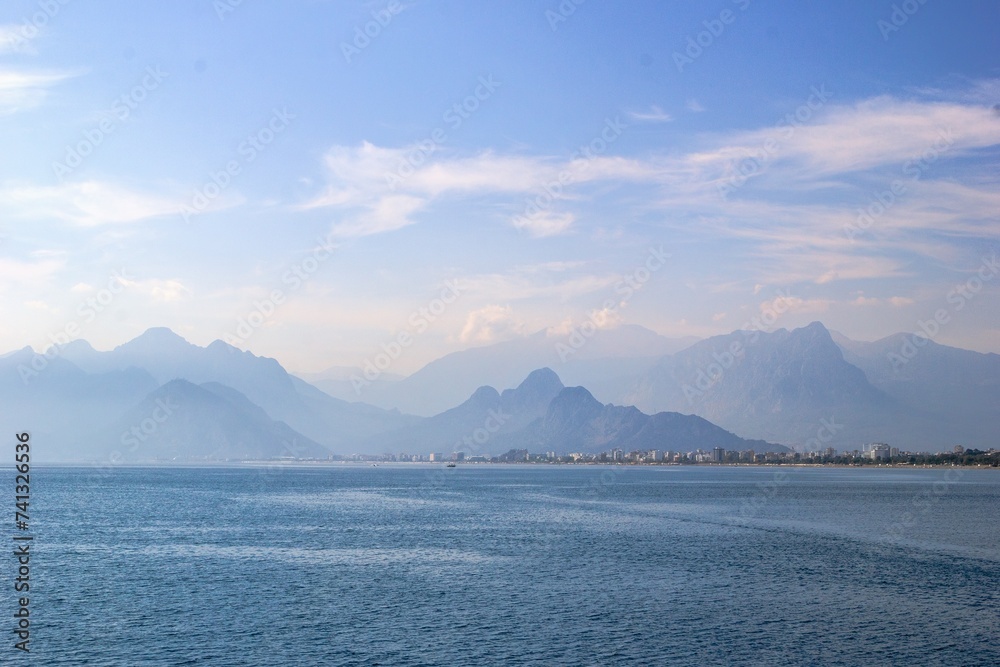 Tranquil seascape with distant mountain range, clear blue sky, and serene atmosphere