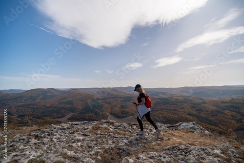 woman on mountain peak looking in beautiful mountain valley in autumn. Landscape with sporty young woman, blu sky in fall. Hiking. Nature