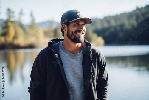 Portrait of a handsome young man smiling at the camera while standing by the lake