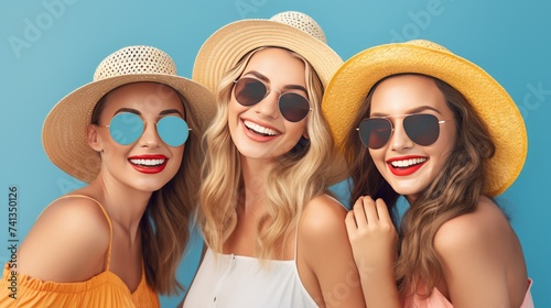 Summer portrait of three beautiful young women smiling, wearing a straw hat on a beach. © Nikolay