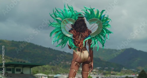 A young girl, dressed in vibrant carnival attire, dances joyfully on the tropical Caribbean island of Trinidad. photo