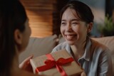 Smiley millennial girl is about to surprise mature father with a birthday surprise at home. Loving adult daughter greets adored father, presenting a present wrapped in a gift box.