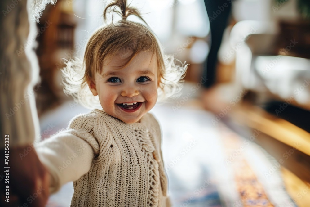 A smiling toddler in a white sweater holds hands with an adult, conveying trust and happiness in a home environment, Generative AI