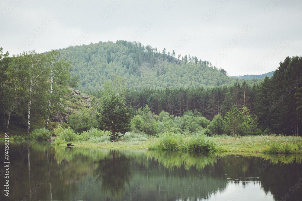 A lake surrounded by trees and mountains, creating a stunning natural landscape A lake surrounded by trees and mountains, creating a stunning natural landscape