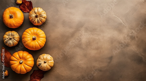 A group of pumpkins with dried autumn leaves and twig, on a brown color marble