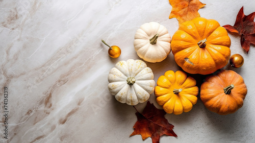 A group of pumpkins with dried autumn leaves and twig, on a light gray color marble