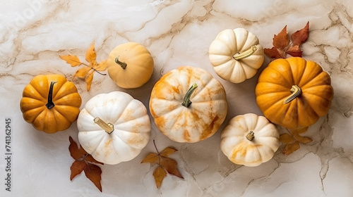 A group of pumpkins with dried autumn leaves and twig, on a beige color marble