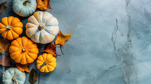 A group of pumpkins with dried autumn leaves and twig, on a light blue color marble