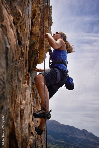Woman, hiking and rock climbing for workout in outdoors, challenge and rope for training. Female person, cliff and extreme sport for exercise or fitness, mountain and support to explore in nature