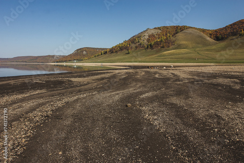 a dirt road leading to a lake with mountains in the background