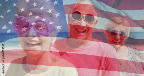 Image of flag of usa over caucasian senior friends on beach in summer