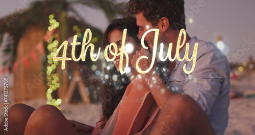 Independence day text and spots of light against caucasian couple embracing each other at the beach
