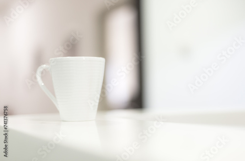 White coffee mug on counter desk in reception room with real natural bright daylight