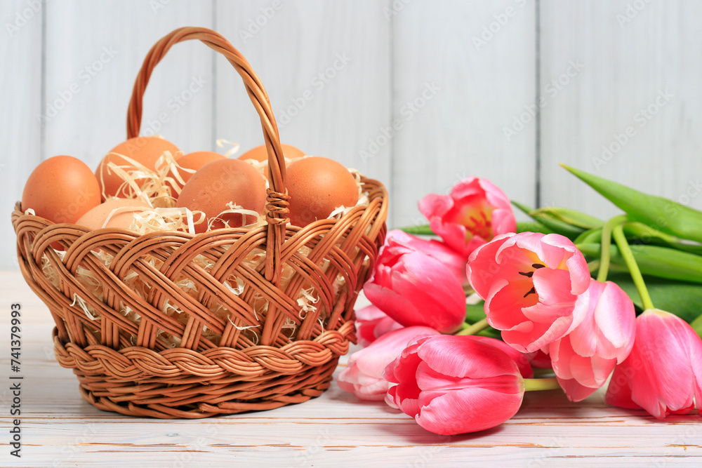 Eggs in a wicker basket and bouquet of pink tulips. Eggs in a wicker basket and bouquet of pink tulips.