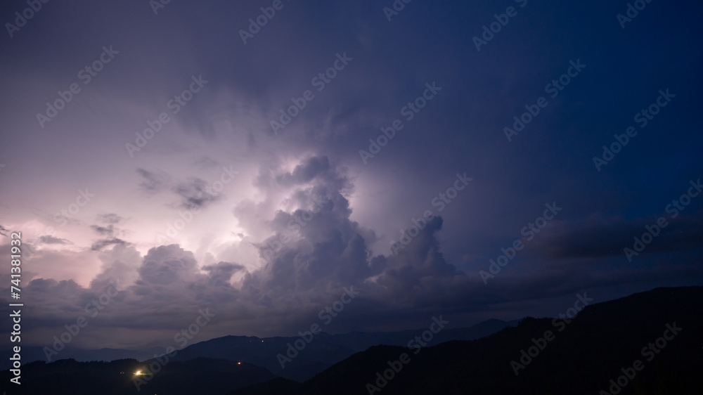 Evening thunderstorm with lightning in the mountains. Dramatic clouds during a thunderstorm pierce the light of lightning in a mountainous area. - obrazy, fototapety, plakaty 