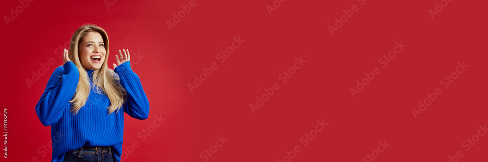 Pretty young woman expressing happy and shocked, excited emotions against red studio background. Sales season. Concept of emotions, youth, fashion, expression. Banner. Empty space to insert text, ad Pretty young woman expressing happy and shocked, excited emotions against red studio background. Sales season. Concept of emotions, youth, fashion, expression. Banner. Empty space to insert text, ad