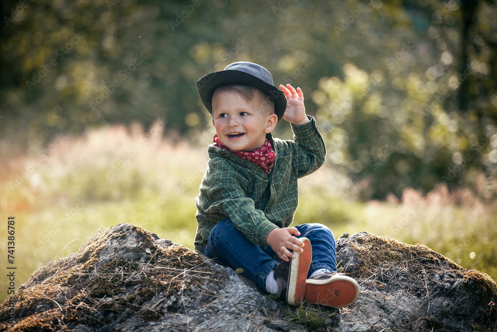 Cute Little Happy Boy with Hat Sitting in Summer Forest Cute Little Happy Boy with Hat Sitting in Summer Forest