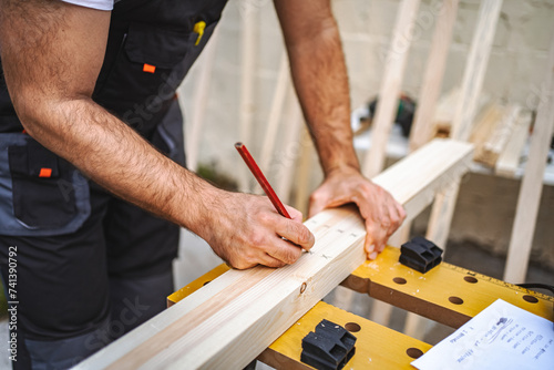 Unrecognizable men measuring wooden plank outdoors