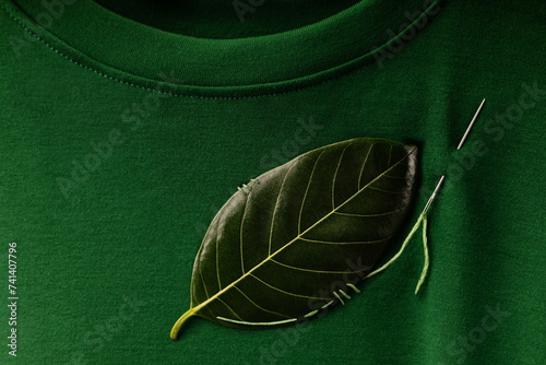 ESG and Sustainability Lifestyle. Environmental Care Concept. Close up of a Green Leaf Embroidered with a Sewing Needle on t-shirt. Eco-Friendly, Organic Cloth #741407796