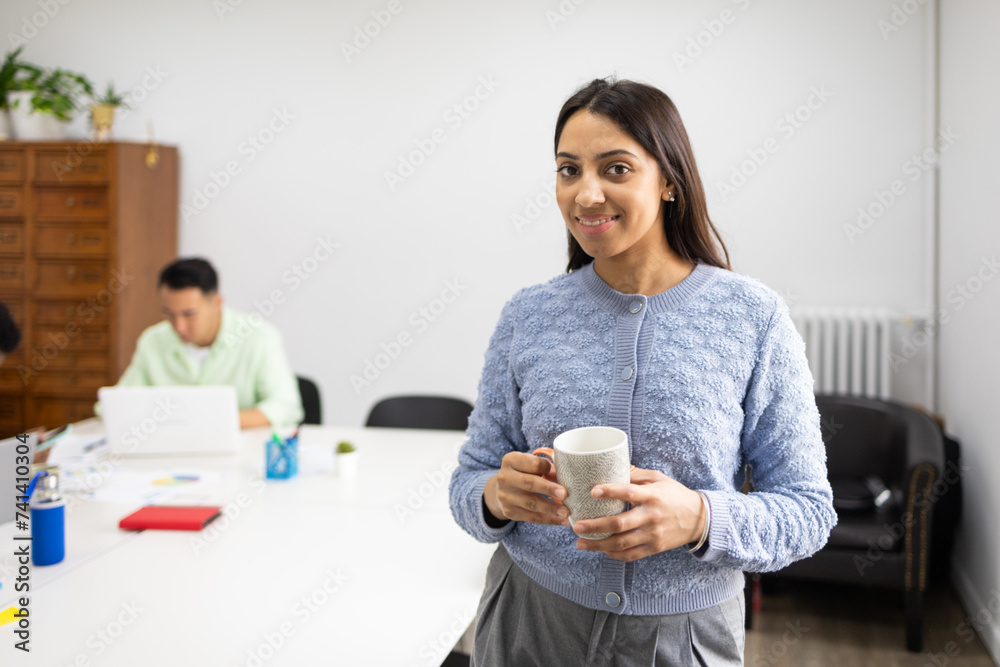 Smiling businesswoman with coffee cup in office Smiling businesswoman with coffee cup in office