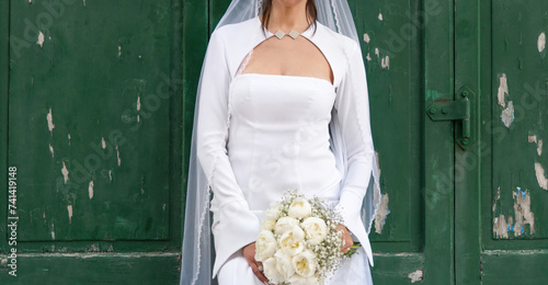 Sposa con bouquet di fiori bianchi su fondo legno verde