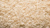 Dry white rice grains. Textured background. Top view. Copy space. Concept of uncooked food, dietary staple, cereal grain, and agricultural product