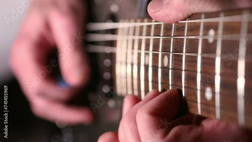 Guitarist's fingers playing on fretboard photo