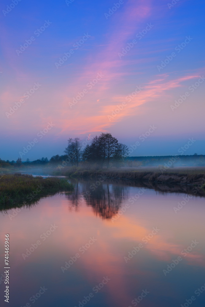 Landscape after sunset with beautiful reflection of the sky and trees in the river