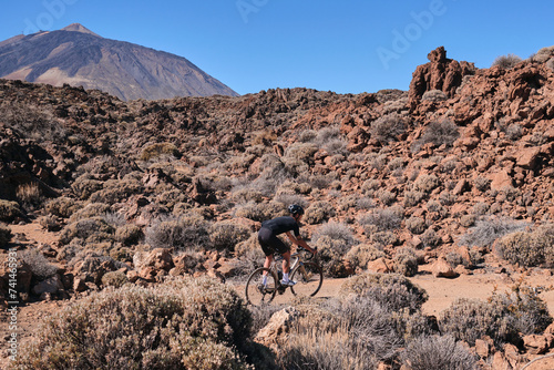 Cyclist practicing on gravel road. Fit man cyclist riding a gravel bike on gravel road with a view of the Teide volcano on Tenerife Canary Island, Spain. Cycling gravel adventure. Effort mood.