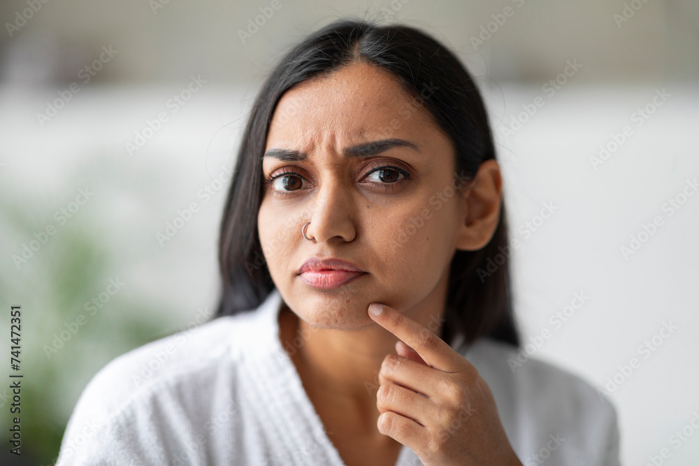 Closeup of upset young indian woman touching her face