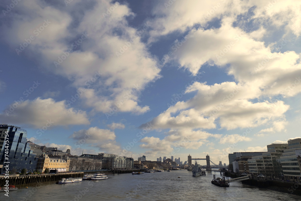 Puffy white clouds drift over central London as seen looking down the Thames towards tower bridge.