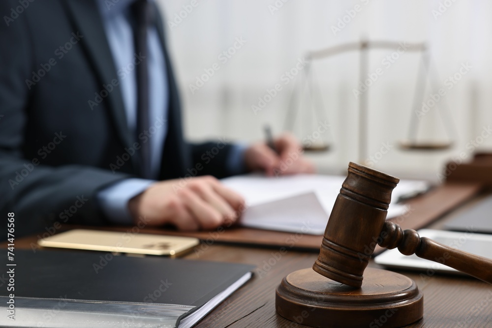Lawyer working with documents at wooden table, focus on gavel Lawyer working with documents at wooden table, focus on gavel