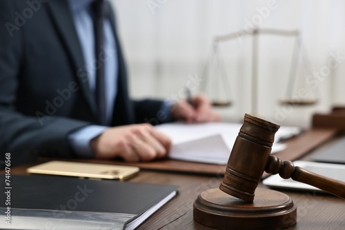 Lawyer working with documents at wooden table, focus on gavel