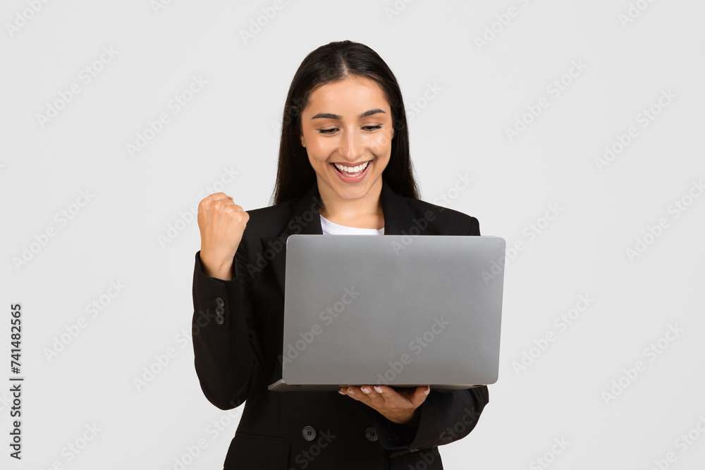 Joyful young businesswoman with laptop celebrating success Joyful young businesswoman with laptop celebrating success