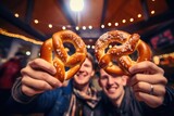 Two people holding up pretzels in front of their faces. Great for food and friendship concepts