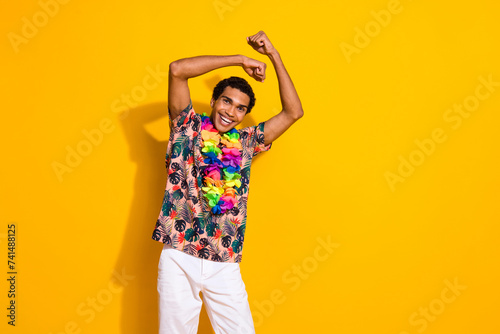 Photo of young funny guy tourist at hawaii beach party waving hands keep dancing boogie woogie isolated on yellow color background photo