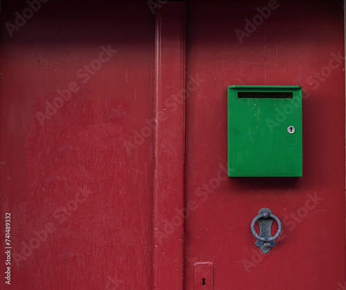 Closeup of an old red door with a green mailbox in the old town of Bern
