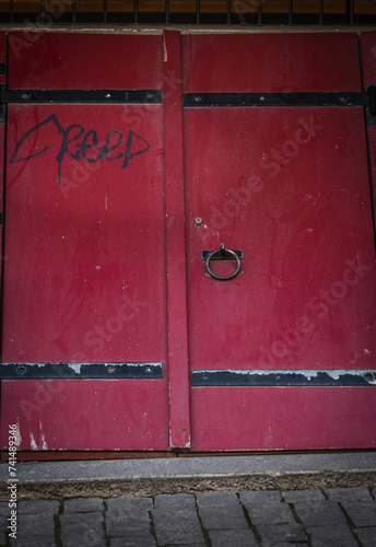 Closeup of an old red door with the word Creep written on it in the old town of Bern