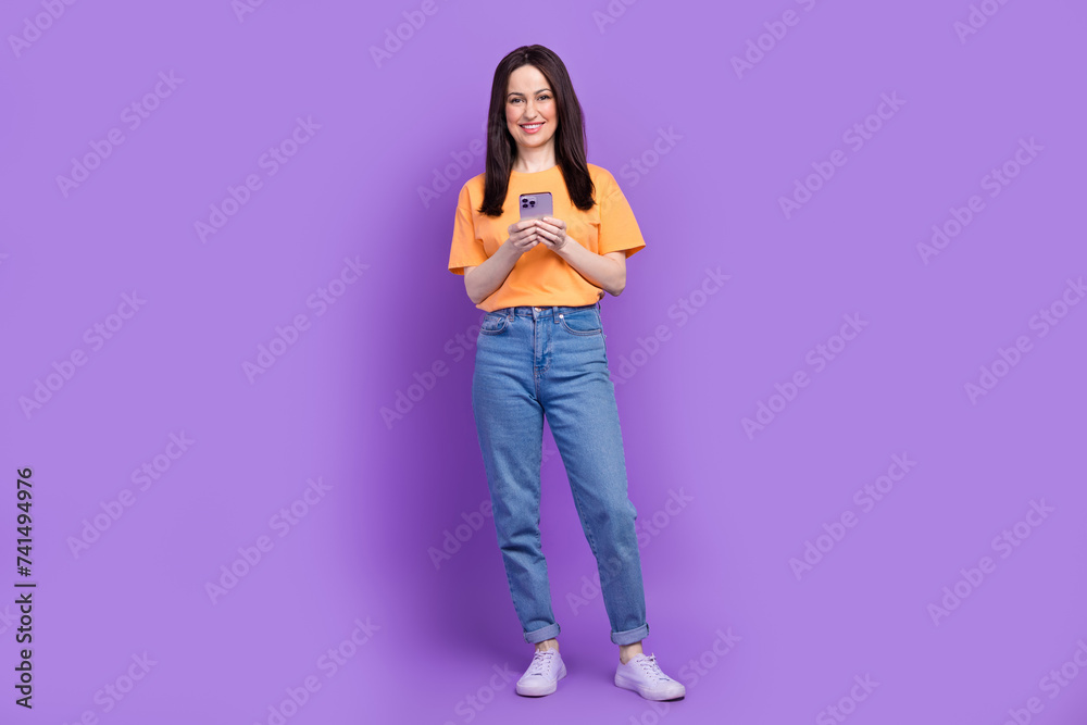 Full body size photo of satisfied seller woman using smartphone to send financial agreement email isolated on purple color background Full body size photo of satisfied seller woman using smartphone to send financial agreement email isolated on purple color background