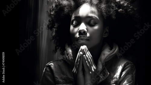 Black and white portrait of emotionally and desperately praying young woman on dark background